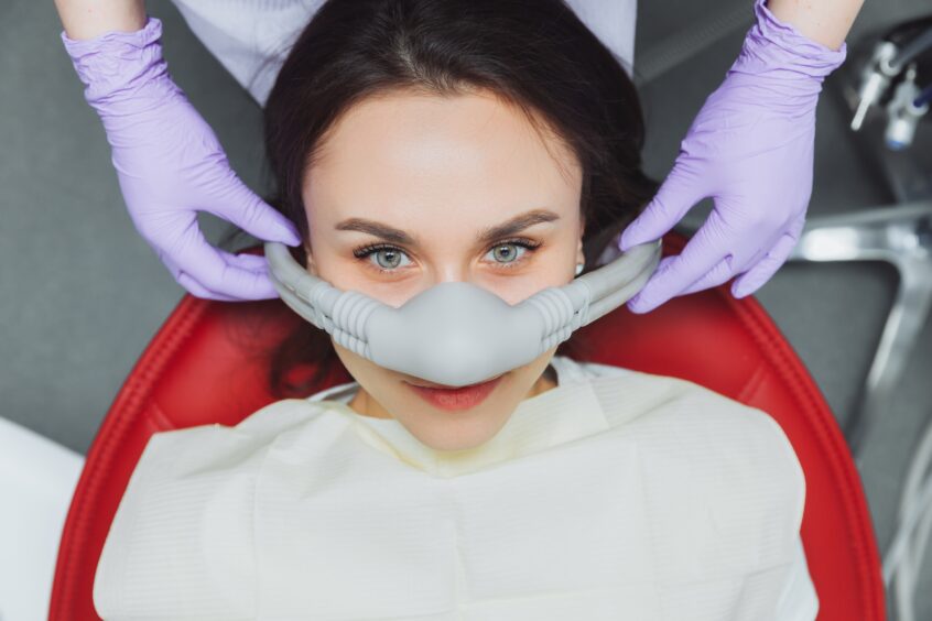 Woman wearing nose piece for laughing gas looking at camera