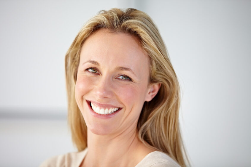 smiling Australian woman with perfect smile from her dental implants